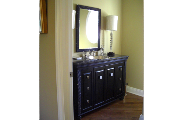 A vanity cabinet built around a black mirror with carved embossed square boxes and small mirrored square inlays.
